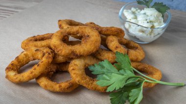 Bar menüsü için yakın plan görüntü. Sulu çıtır soğan halkaları maydanoz yapraklı bir zanaat zemininde yatıyor. Tabağın adı için boşluk.
