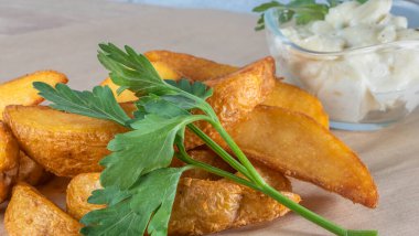 Soslu patates dilimleri ve parşömen üzerinde maydanoz. Fast food kavramları.