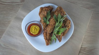 Beyaz tabakta soslu haşlanmış tavuk şeritleri. Kızarmış tavuk kızartması. Fast food beyaz tabak arka planda. Fast food kavramları.