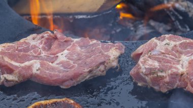Barbeküde çiğ biftek. Barbekü Izgarasında Biftek Atışı 'nın hemen üstünde. Barbekü yemeği yakın çekim fotoğrafı. Sokak yemekleri konsepti. Çiğ domuz eti ya da sığır eti kömür fırınında kızarıyor..