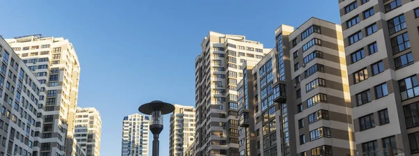 Yüksek binaların yakınındaki sıkışık avlu. Mavi gökyüzünün arka planında büyük bir apartman. Komşuluk kavramları.