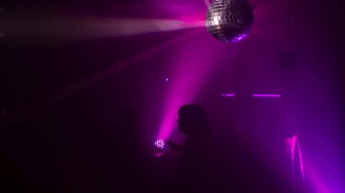 Disko gece kulübünde DJ 'in sahnede yaptığı müzikle dans eden insanların silueti. Disko topuyla parti atmosferi