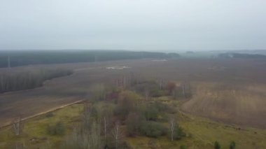 Sisteki sonbahar tarım alanlarının en üst görüntüsü. Büyük bir şehir ve göl yakınlarındaki sonbahar tarlalarını kaplayan sis ve sis. Kırsal kavram.