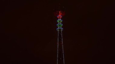 Minsk 'teki aydınlanmış TV yayın kulesinin panoramik görüntüsü. Minsk 'teki TV Kulesi' nin gece manzarası. Şenlik ve teknoloji kavramları. 4k video.