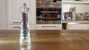 Mutfak arka planında profesyonel biber öğütücüsü. Büyük cam biber değirmeni ya da ahşap masada biberlik. Pişirme kavramları. Metin için boşluk.