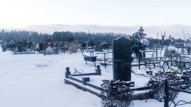 Mezarlıkta kar yağıyor. Kışın kar altında geleneksel mezarlık. Mezarlıkta mezar taşı var. Kışın karla kaplı bir mezarlık. Dramatik gökyüzü arkaplanı. Metin için boşluk.