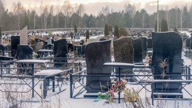 Mezarlıkta kar yağıyor. Kışın kar altında geleneksel mezarlık. Mezarlıkta mezar taşı var. Kışın karla kaplı bir mezarlık. Dramatik gökyüzü arkaplanı. Metin için boşluk.