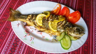 Beyaz tabakta ızgara alabalık, sebze ve limon. Üst Manzara. Ulusal Mutfak.