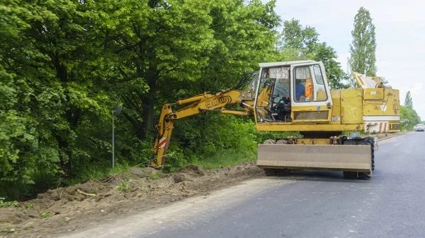 Bir yol inşaatı. Dünya hareketi. İnşaat alanında bir kazıcı. Ağır makineler kavramı.