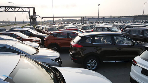 Aerial view of new cars lined up parking outside factory on car factory background.