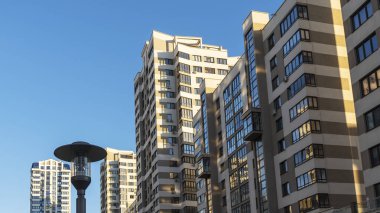 Yüksek binaların yakınındaki sıkışık avlu. Mavi gökyüzünün arka planında büyük bir apartman. Komşuluk kavramları.