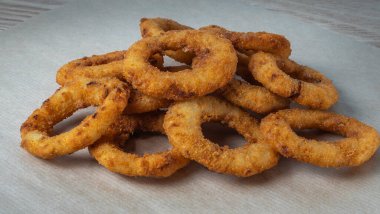 Bar menüsü için yakın plan görüntü. Sulu çıtır soğan halkaları maydanoz yapraklı bir zanaat zemininde yatıyor. Tabağın adı için boşluk.