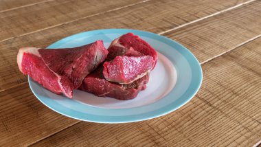 Aşçılık için bir parça et. Ev yemeği tariflerini gösteren bir resim. Ham Omuz Meydanı, tahta arka planda tabakta kesik. Metin için boşluk.