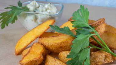 Soslu patates dilimleri ve parşömen üzerinde maydanoz. Fast food kavramları.