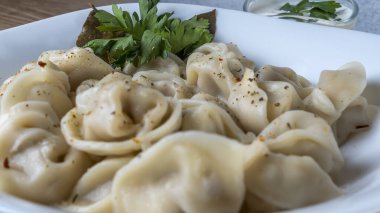 Kaynamış etli börek. Rus kaynamış pelmeni 'nin beyaz tabakta yakın plan görüntüsü. Haşlanmış ev yapımı Rus köftesi ya da etli pelmeni..