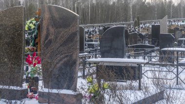 Mezarlıkta kar yağıyor. Kışın kar altında geleneksel mezarlık. Mezarlıkta mezar taşı var. Kışın karla kaplı bir mezarlık. Dramatik gökyüzü arkaplanı. Metin için boşluk.