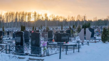 Karanlık mezar taşları ve ağaçlarla kaplı bir mezarlığın üzerinde kış günbatımı. Ölümden sonra. Samsara kavramları. Ölülerin dirileceği umudu. Metin için boşluk.