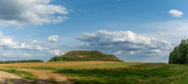 Kapalı şehir çöplüğü. Bölgenin restorasyonu. Büyük bir çöp yığınının peyzajı. Arka planda bir metropol ve bulutlu mavi bir gökyüzü var. Ekolojik sorun.