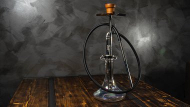 Ahşap masadaki cam kaseli modern nargile. Gri duvar arkaplanı.