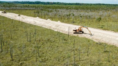 Kazı makinesi bataklıktan geçen yoldaki karmaşada çalışıyor, Olmany. Ekolojik bir sorun. Endüstri kavramları.