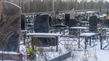 Mezarlıkta kar yağıyor. Kışın kar altında geleneksel mezarlık. Mezarlıkta mezar taşı var. Kışın karla kaplı bir mezarlık. Dramatik gökyüzü arkaplanı. Metin için boşluk.