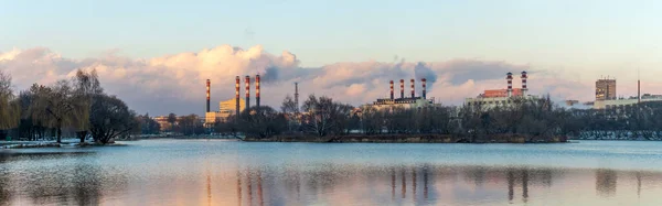 구름낀 하늘을 배경으로 발전소의 굴뚝에서 흡연하는 생태학적 문자를 발전소가 호수의 — 스톡 사진