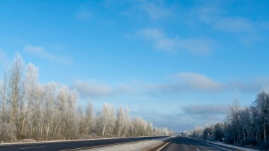 Kışın kırsal kesimde köy yolu. Siyah temiz asfalt. Kış yolu karla kaplı tarlalardan geçiyor. Ulaşım kavramları. Metin için boşluk.