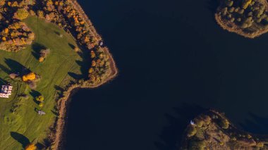 Sonbahar ormanı ve göl manzarası. Orman gölü üzerinde sonbahar güneşli bir akşam. Kırsal alan.