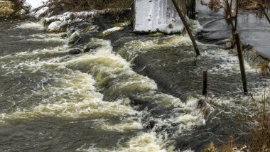 Bir yaya köprüsünün altındaki kış nehrinde kaynar su. Soyut arkaplan. Mesaj için yer var. Doğa kavramları.