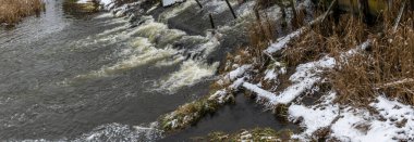 Bir yaya köprüsünün altındaki kış nehrinde kaynar su. Soyut arkaplan. Mesaj için yer var. Doğa kavramları.