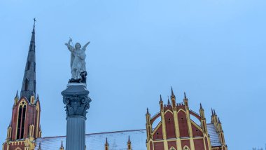 Geleneksel bir Başmelek Michael heykeli dramatik gökyüzüne ve kilise kulesine karşı şeytana mızrakla vuruyor. Mesaj için yer var. Din kavramları.