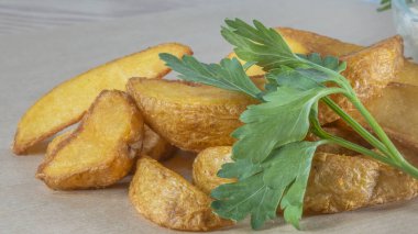 Soslu patates dilimleri ve parşömen üzerinde maydanoz. Fast food kavramları.