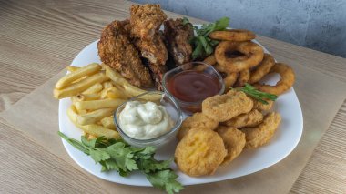 Atıştırmalık tabaklar - peynir çubukları, tavuk nugget, soğan halkaları, patates kızartması ve soslar. Bira tahtası. Yatay fotoğraf. Bar menüsü için fotoğraf.
