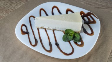 Beyaz tabakta nane yaprağı olan sade New York peynirli kek dilimi. Kahve molası kavramları. Yatay bileşim. Tasarım menüsü kafesi veya şekerlemesi için resim.