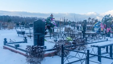 Mezarlıkta kar yağıyor. Kışın kar altında geleneksel mezarlık. Mezarlıkta mezar taşı var. Kışın karla kaplı bir mezarlık. Dramatik gökyüzü arkaplanı. Metin için boşluk.