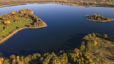 Sonbahar ormanı ve göl manzarası. Orman gölü üzerinde sonbahar güneşli bir akşam. Kırsal alan.