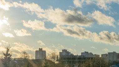 İlk kar şehirdeki yerleşim yerlerini kaplıyor. Güneş ışığı ve bulutlu gökyüzü. Şehir kavramları. Arka planda yüksek binalar var..