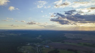 Yeşil tarlalar, orman ve yazın bulutlu mavi gökyüzü. Tarlaları, otları, ağaçları, güneşli gökyüzünü ve yemyeşil yapraklarını içeren soyut bir manzara. İnsansız hava aracıyla manzara.
