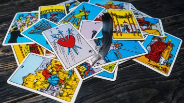 Tahta arka planda tarot kartları ve kuş tüyü. Mistik ve kehanet kavramı. Metin için boşluk.