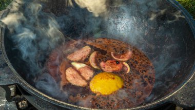 Büyük bir kazanda şarap kaynattım. Sıcak şarap büyük bir tencerede pişirilir. Geleneksel festivalde vitaminler. Çeşitli meyve ve baharatlarla sıcak şarap.