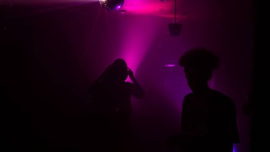 Disko gece kulübünde DJ 'in sahnede yaptığı müzikle dans eden insanların silueti. Disko topuyla parti atmosferi