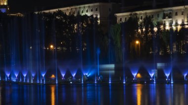Geceleyin bir nehirde çok renkli bir müzik çeşmesi. Aydınlanmadan kaynaklanan gece çeşmesi. Mesaj için yer var. Kutlama konsepti.