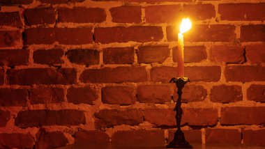 Kırmızı arka planda mum alevi yakın plan. Eritilmiş mum ışığı sınır tasarımı. Uzun pozlama. Karanlık. Gece yanıyor, mum ışığı. Geniş Ekran