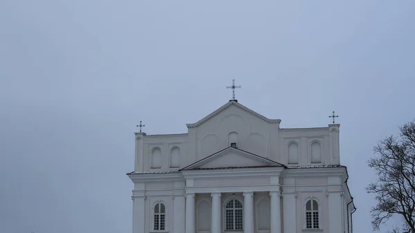 Ostrovets Grodno地域の聖人コスマスとダミアン教会は灰色の空を背景に木の枝を持ちます 崇拝と歴史遺産の概念 — ストック写真