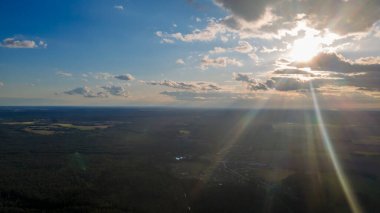 Güneşin ışığı gökyüzündeki bulutların arasından parlıyor. Tüylü bulutların şaşırtıcı bir şekilde gökyüzünde usulca hareket ediyor ve güneş bulutların arasında parıldıyor güzel ışınlar ve merceklerle..
