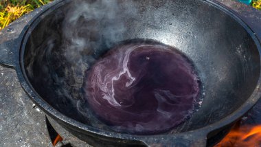 Sıcak kamp ateşinin üstünde, turist tenceresinde sıcak şarap. Ateşin yanında sıcak şarap. Açık havada ateşte pişirilmiş şarap. Piknik. Ateşin yanında romantik bir kaçış..