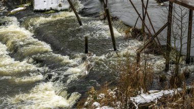 Bir yaya köprüsünün altındaki kış nehrinde kaynar su. Soyut arkaplan. Mesaj için yer var. Doğa kavramları.