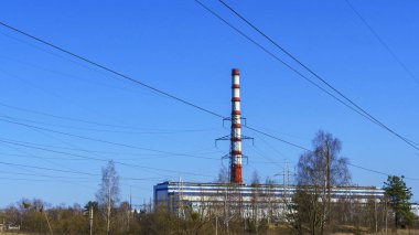 Termik santral bacası ve klasik mavi gökyüzü arka planında elektrik kabloları. Yeşil güç ve ekolojik sorun. Endüstri kavramları.