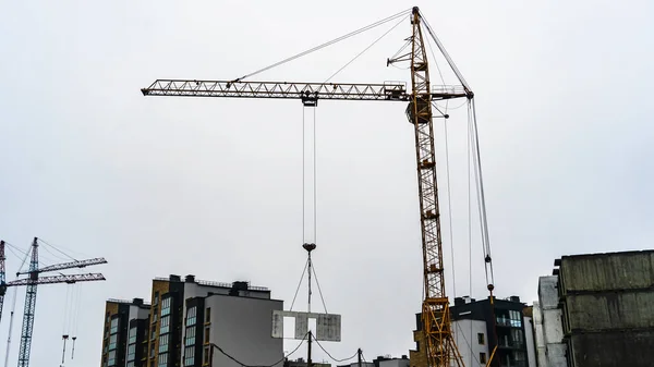 Turmdrehkran Hebt Einen Monolithischen Block Vor Der Kulisse Einer Baustelle — Stockfoto