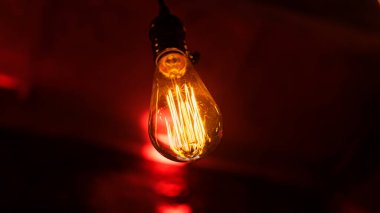 Koyu kırmızı tuğla duvarın arka planında yakın plan güzel sarı parlak ampul. Metin için boşluk.